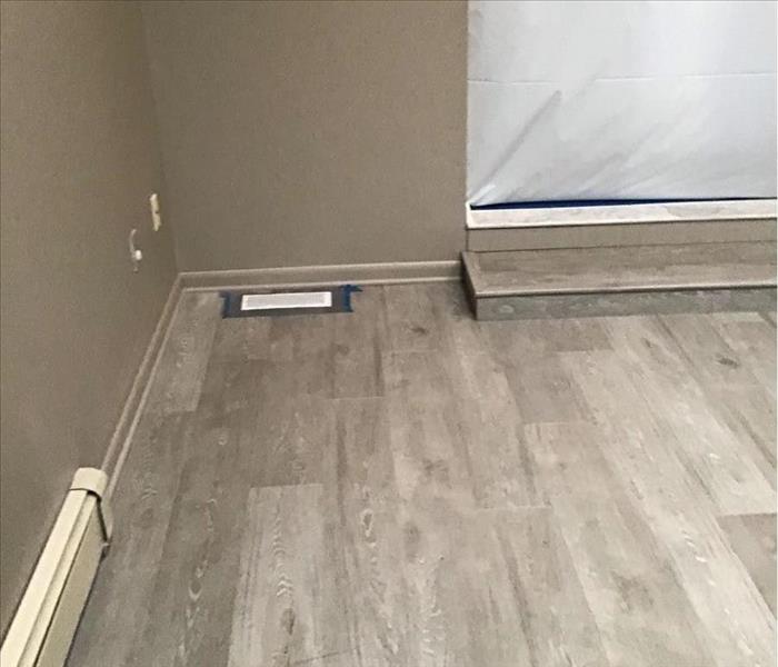 Room with laminate flooring with doorway and vent covered
