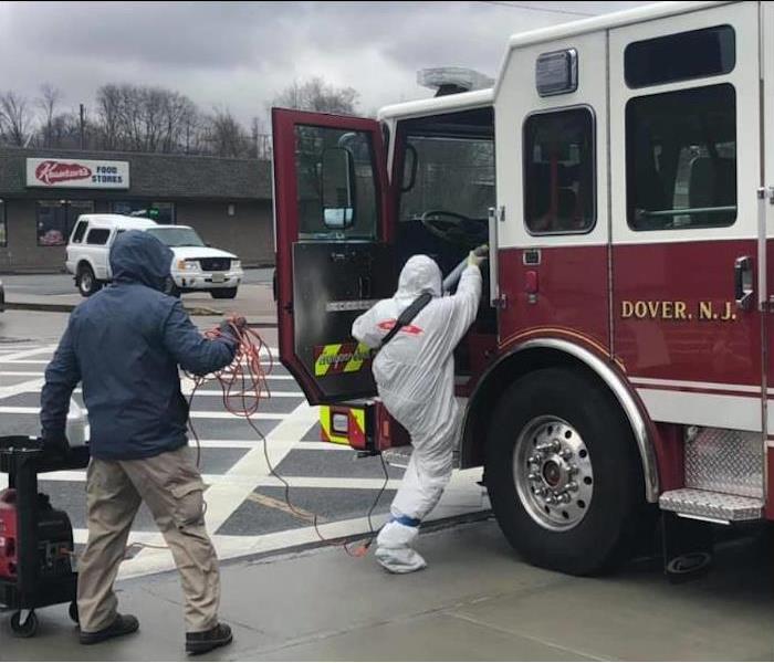male employee in protective covering stepping into a firetruck
