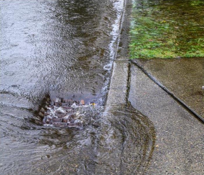 Heavy rain caused flooding in street, water swirling around storm drain