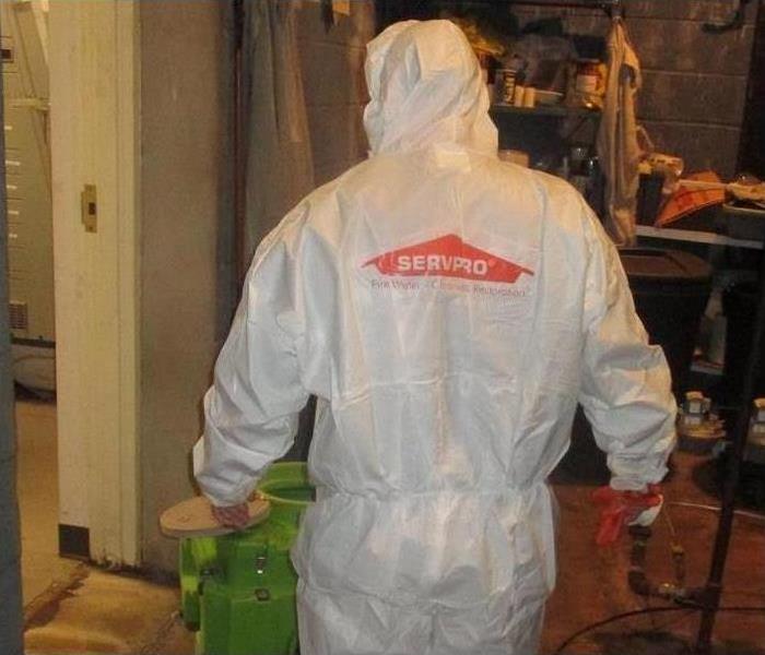 SERVPRO tech, in PPE, cleaning flood damaged room