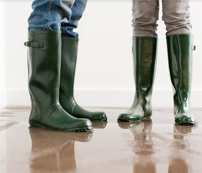 two people standing in rain boots in a flooded room